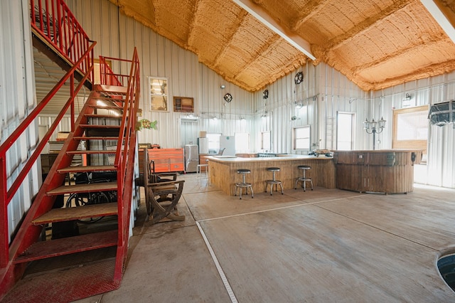 interior space featuring high vaulted ceiling, concrete floors, and stairs