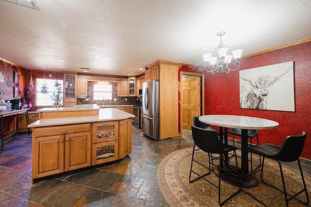 kitchen with visible vents, light countertops, appliances with stainless steel finishes, a center island, and glass insert cabinets