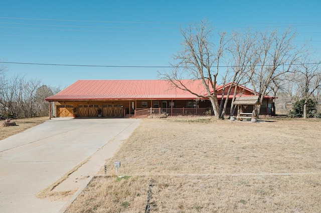 view of front of property with driveway, covered porch, and metal roof