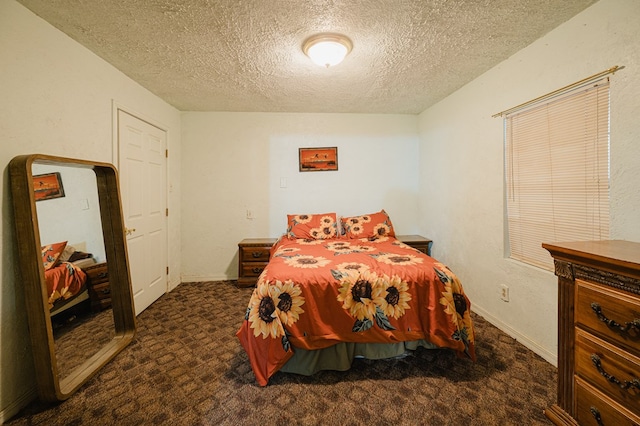 bedroom with dark carpet and a textured ceiling