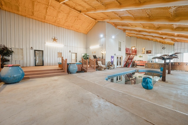 interior space with high vaulted ceiling, concrete floors, and metal wall