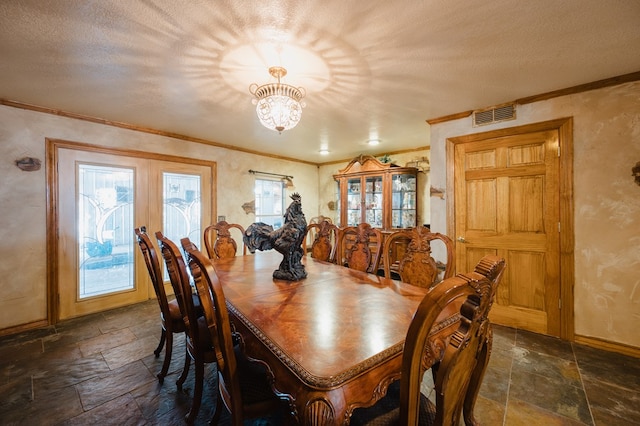 dining room featuring a textured ceiling, ornamental molding, visible vents, and stone tile floors