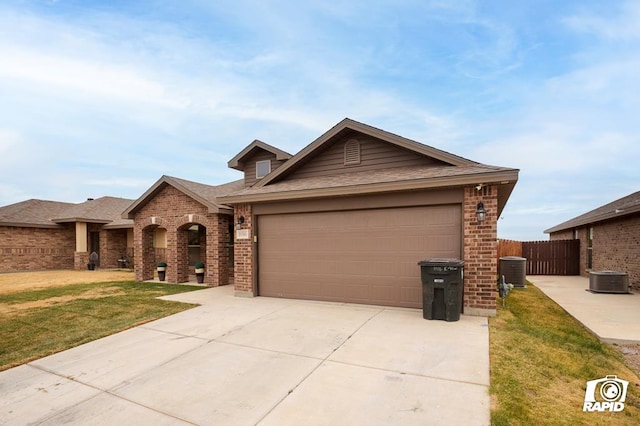 ranch-style house featuring a garage, a front yard, and central air condition unit