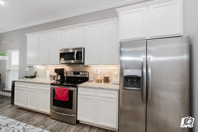 kitchen with appliances with stainless steel finishes, light stone counters, white cabinets, and backsplash