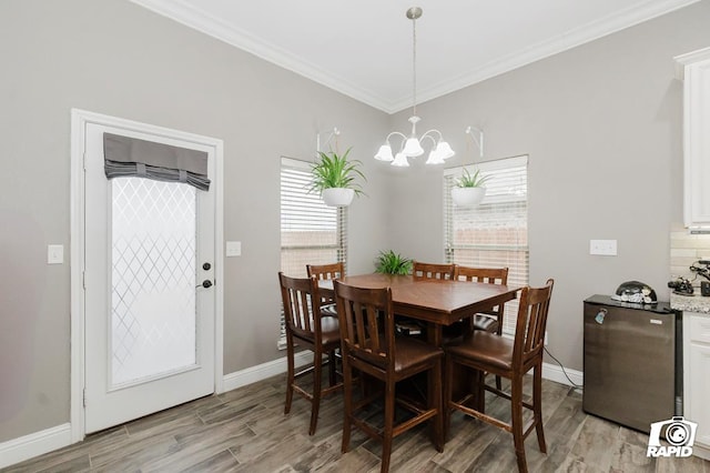 dining area with ornamental molding, an inviting chandelier, and light wood-type flooring