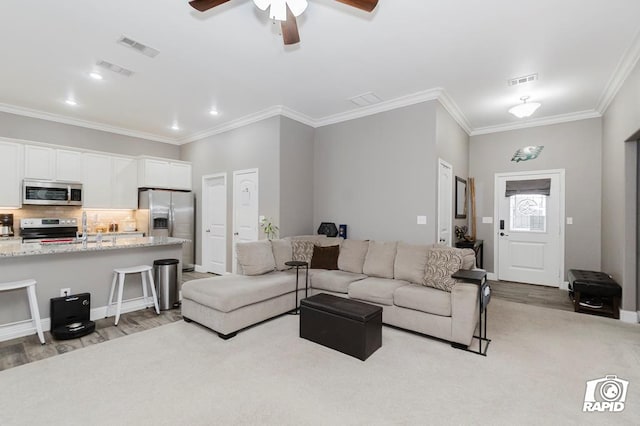 living room with ornamental molding, ceiling fan, and light hardwood / wood-style floors