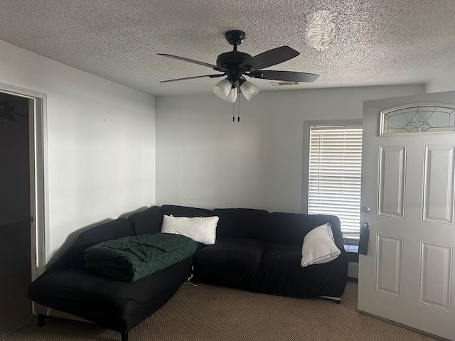 living room featuring ceiling fan, light colored carpet, and a textured ceiling