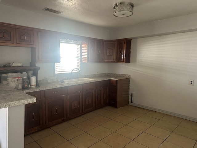 kitchen featuring sink, light tile patterned floors, and dark brown cabinets