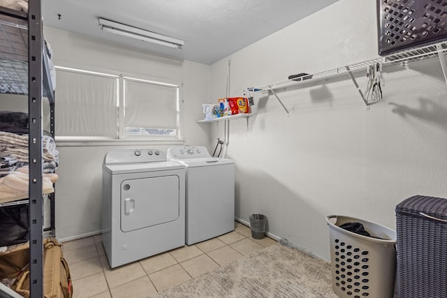 clothes washing area featuring light tile patterned floors, a textured ceiling, and washing machine and clothes dryer