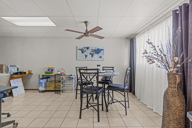 tiled dining space with ceiling fan and a paneled ceiling