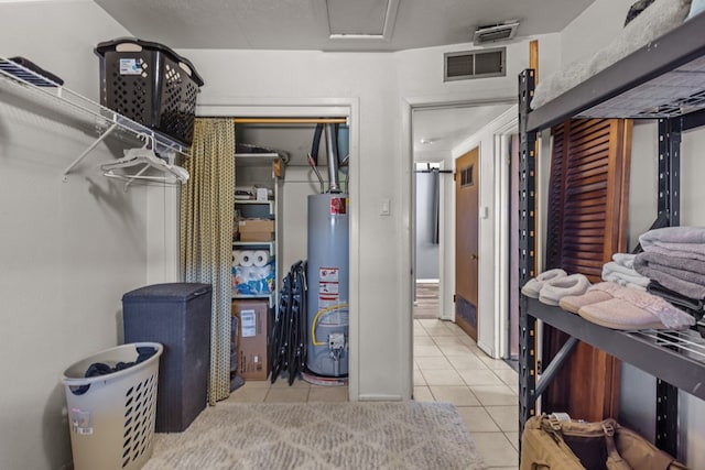 walk in closet featuring water heater and light tile patterned floors