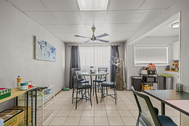 tiled dining space featuring a paneled ceiling and ceiling fan