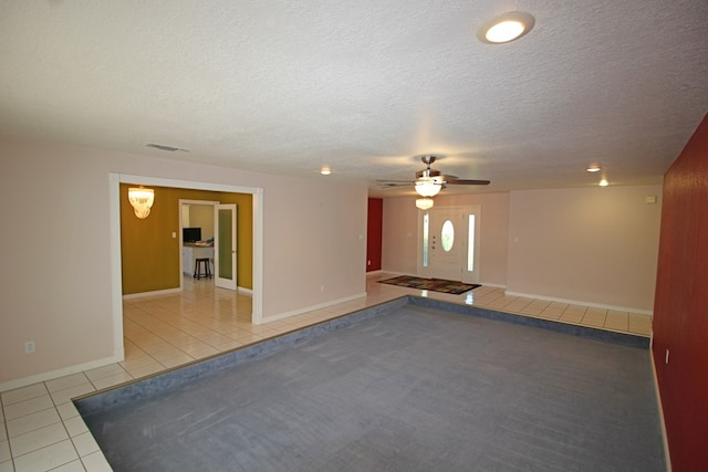 tiled spare room with ceiling fan and a textured ceiling