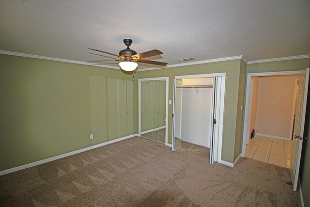 unfurnished bedroom featuring ceiling fan, light colored carpet, a textured ceiling, and crown molding