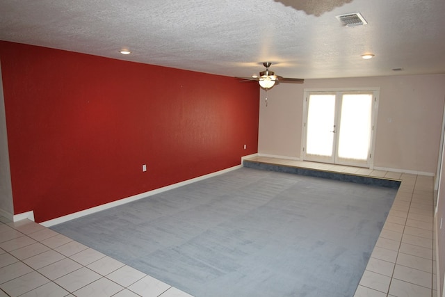 unfurnished room featuring ceiling fan, light tile patterned flooring, a textured ceiling, and french doors