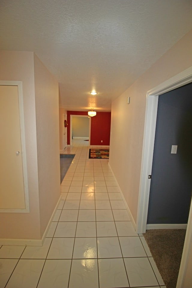 hall featuring light tile patterned flooring and a textured ceiling