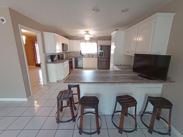 kitchen featuring a breakfast bar area, kitchen peninsula, white cabinets, and appliances with stainless steel finishes