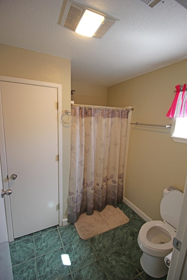 bathroom with toilet, a textured ceiling, tile patterned floors, and curtained shower