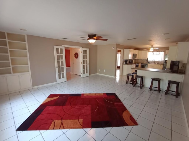 unfurnished living room featuring french doors, sink, ceiling fan, and light tile patterned flooring