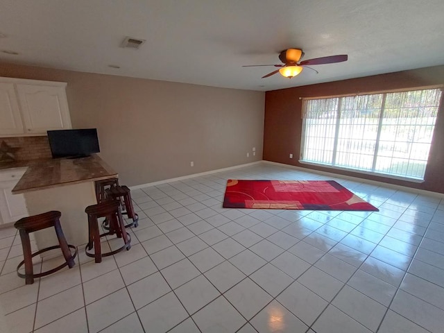 interior space with light tile patterned floors and ceiling fan