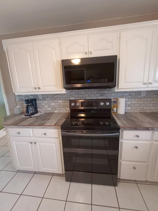 kitchen with white cabinets, black electric range oven, light tile patterned flooring, and tasteful backsplash