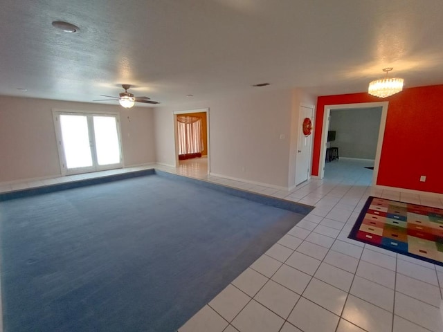 spare room featuring ceiling fan with notable chandelier, light tile patterned floors, and a textured ceiling