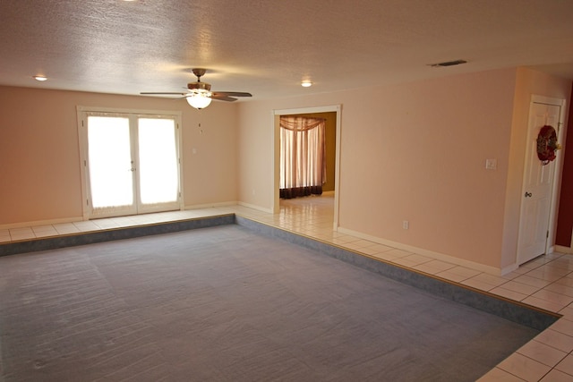 empty room featuring ceiling fan, light tile patterned floors, a textured ceiling, and french doors