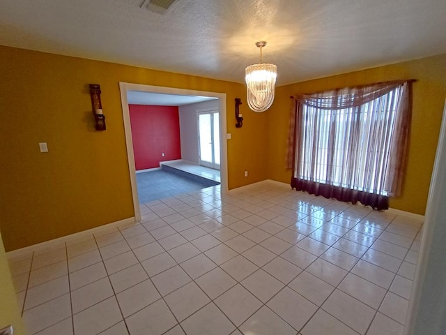 tiled spare room with a notable chandelier