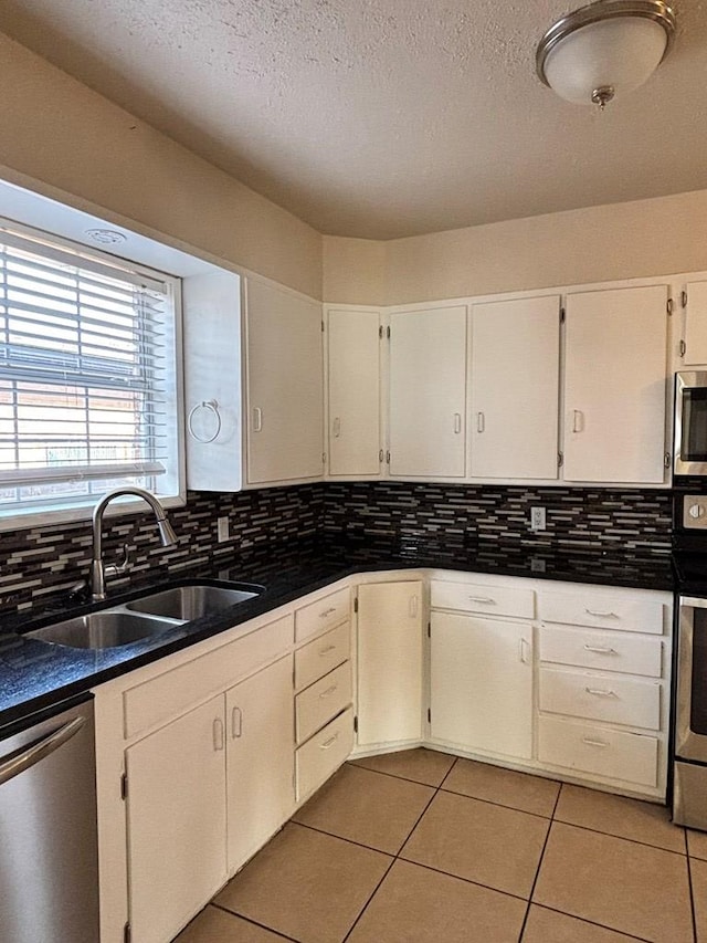 kitchen with white cabinetry, sink, a textured ceiling, light tile patterned floors, and appliances with stainless steel finishes