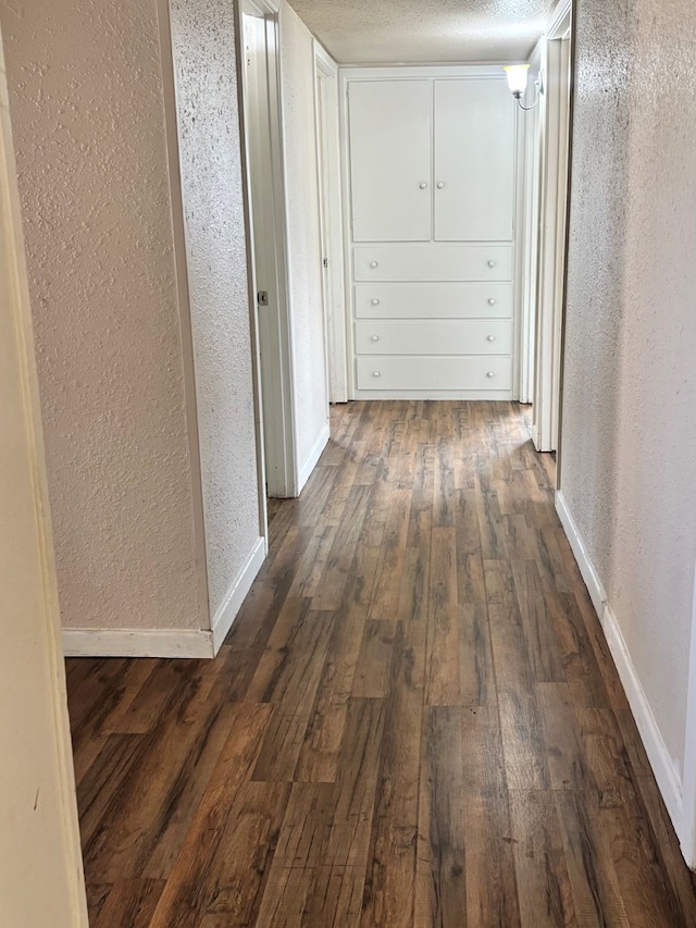 corridor featuring a textured ceiling and dark wood-type flooring