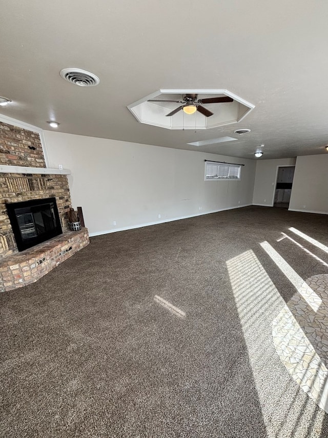 unfurnished living room featuring carpet flooring, ceiling fan, and a brick fireplace