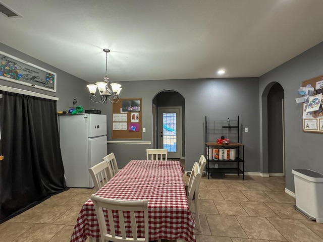 dining space with light tile patterned floors and an inviting chandelier