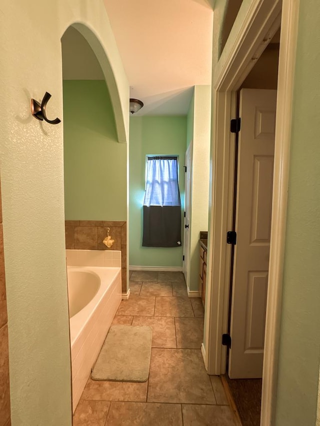 bathroom featuring tile patterned flooring, vanity, and a tub to relax in