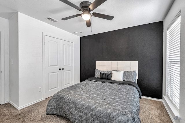 carpeted bedroom featuring a closet, visible vents, ceiling fan, and baseboards