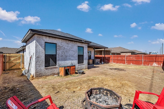 rear view of property with a fire pit, a fenced backyard, and brick siding