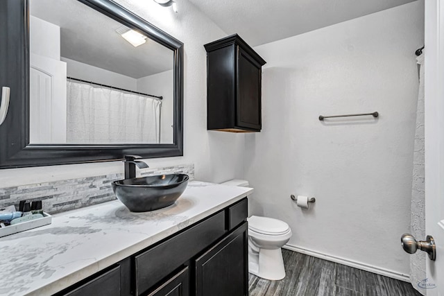 bathroom with vanity, toilet, wood finished floors, and baseboards