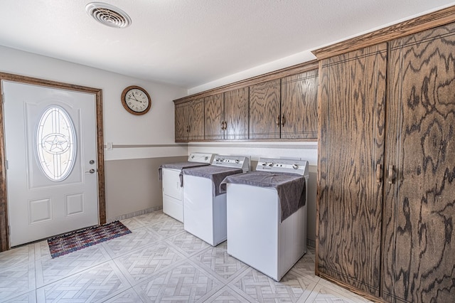 laundry room featuring a textured ceiling, cabinets, and washing machine and clothes dryer