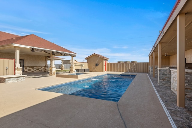 view of swimming pool featuring pool water feature, a patio, ceiling fan, and a storage unit