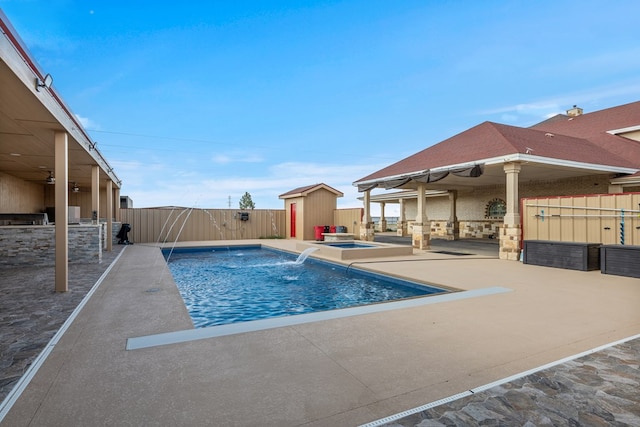 view of swimming pool with pool water feature, a patio area, exterior kitchen, and an in ground hot tub