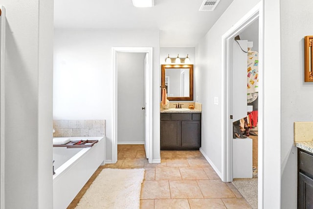 bathroom with tile patterned flooring, vanity, and a tub to relax in