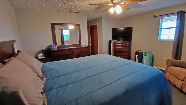 bedroom with ceiling fan and a textured ceiling