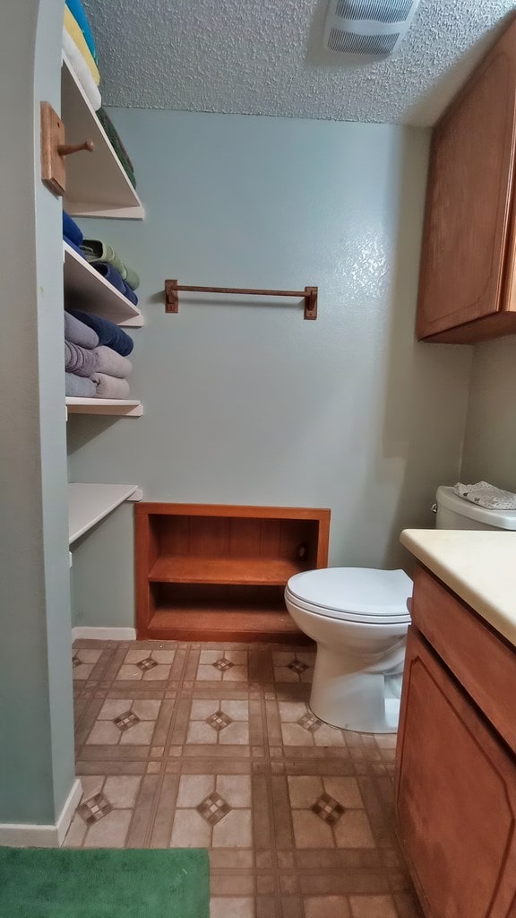 bathroom featuring tile patterned floors, vanity, toilet, and a textured ceiling