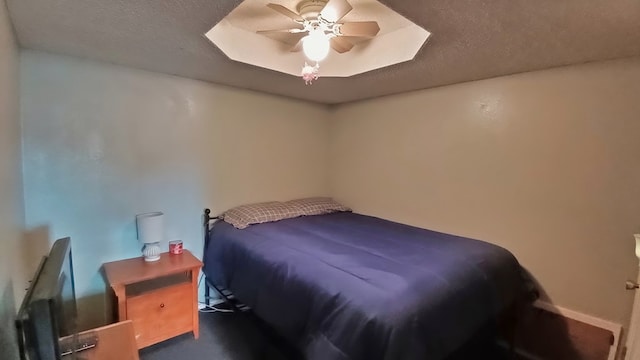 bedroom featuring ceiling fan, a raised ceiling, and a textured ceiling