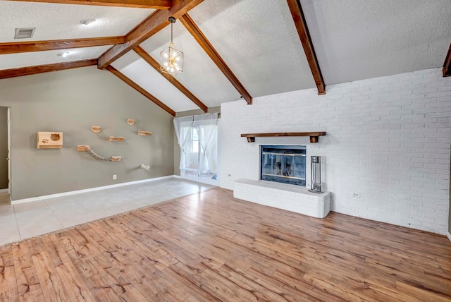 unfurnished living room featuring light hardwood / wood-style flooring, beamed ceiling, and a textured ceiling