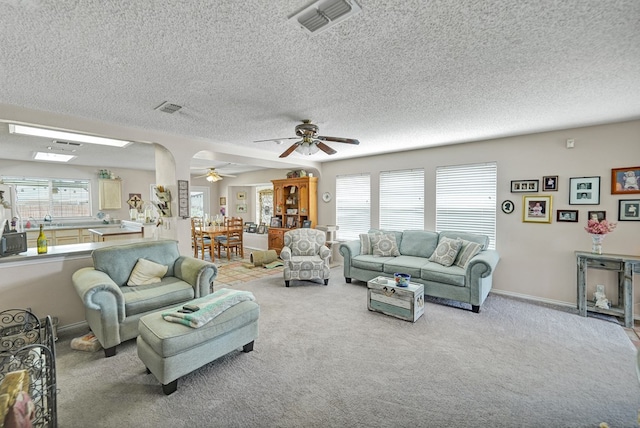 carpeted living room featuring visible vents, ceiling fan, a textured ceiling, and baseboards