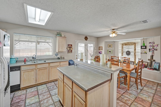 kitchen with fridge with ice dispenser, light brown cabinets, visible vents, and a sink