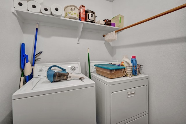 washroom with laundry area, washing machine and dryer, and a textured wall