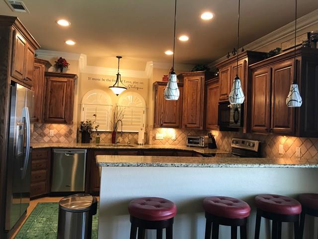 kitchen featuring pendant lighting, light stone countertops, a kitchen breakfast bar, and appliances with stainless steel finishes