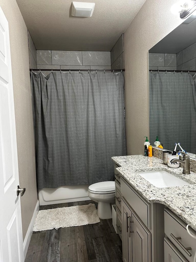 bathroom with curtained shower, hardwood / wood-style floors, a textured ceiling, toilet, and vanity