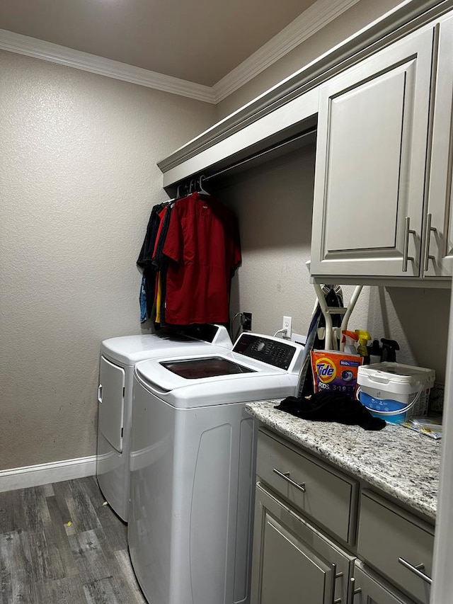 laundry area featuring washing machine and dryer, crown molding, dark wood-type flooring, and cabinets